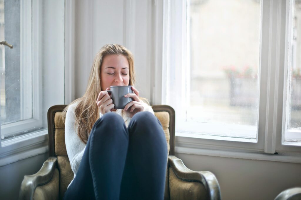 Woman enjoying a warm drink in a cozy armchair by a window, embracing relaxation..Best IELTS Coaching Online